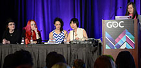 A panel of speakers with a podium in the middle and tables on either side with live speakers.